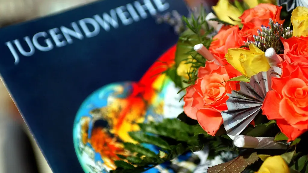 Eine-Jugendweihe-Urkunde-liegt-in-der-Stadthalle-in-Burg-neben-einem-Blumenstrauss