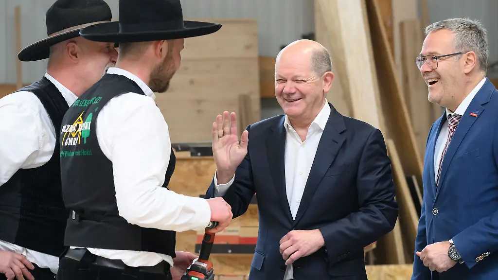 Bundeskanzler-Olaf-Scholz-SPD-3-v-l-scherzt-bei-seinem-Besuch-in-einem-Dresdner-Handwerksbetrieb-im-Holzbau-mit-den-Zimmermeistern-Ralf-Lepski-l-Felix-Lepski-2-v-l-und-Joerg-Dittrich-r-dem-Praesidenten-des-Zentralverbandes-des-Deutschen-Handwerks-ZDH-und-Praesident-der-Handwerkskammer-Dresden