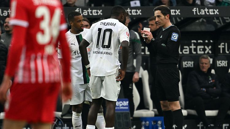 Benjamin Brand erklärt Marcus Thuram, warum es doch keinen Elfmeter gab.