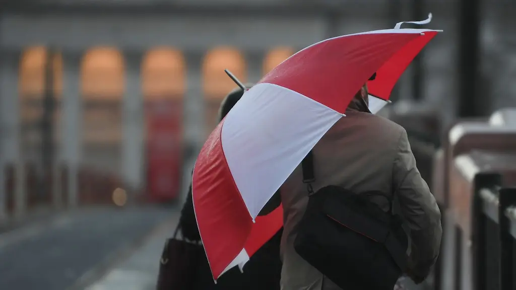 Ein-Fussgaenger-schuetzt-sich-auf-der-Ignatz-Bubis-Bruecke-vor-Wind-und-Regen