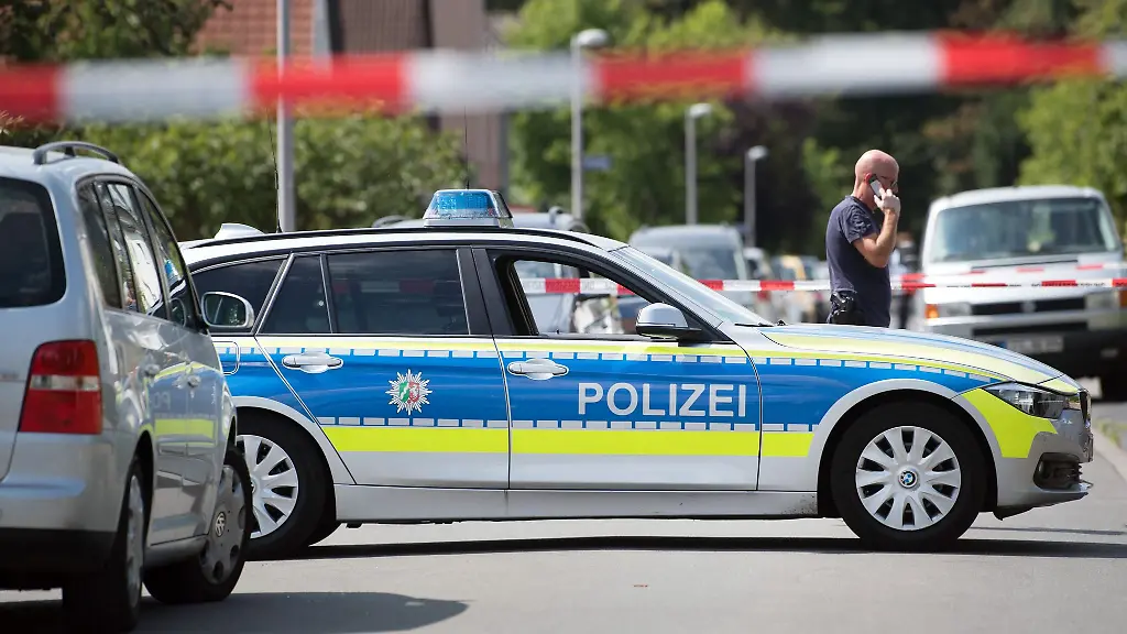 Polizeiwagen-und-Beamte-stehen-auf-einer-abgesperrten-Strasse
