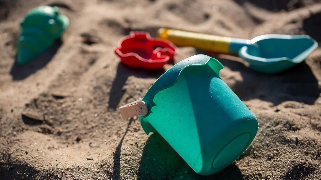 Sandspielzeug-liegt-auf-einem-Spielplatz-in-einem-Sandkasten
