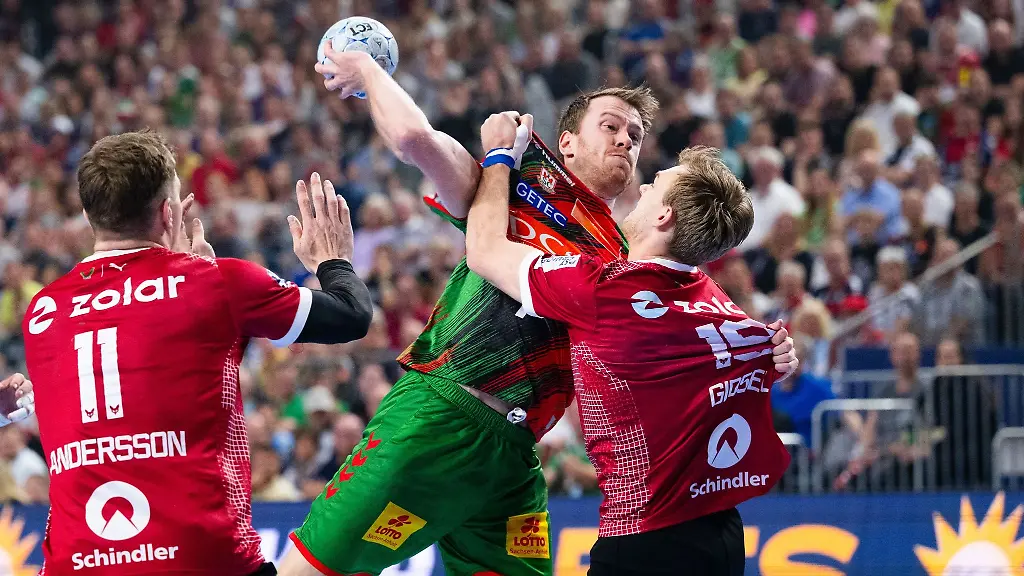 Berlins-Lasse-Andersson-l-und-Mathias-Gidsel-r-versuchen-Magdeburgs-Felix-Claar-am-Wurf-zu-hindern