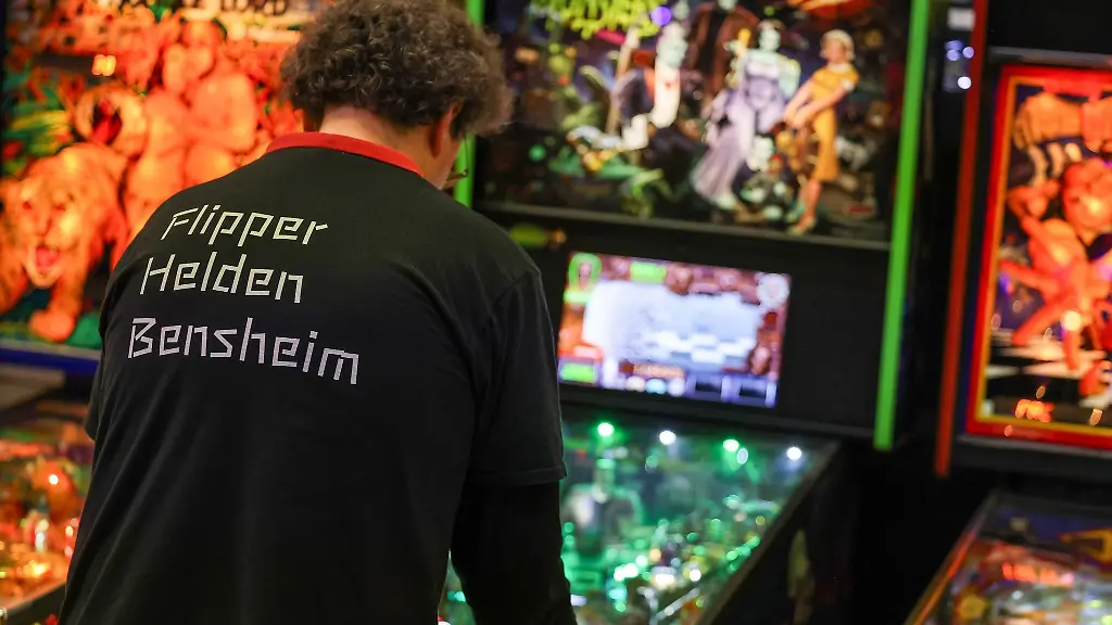 Teilnehmer-stehen-bei-der-Pinball-Convention-an-Flippergeraeten