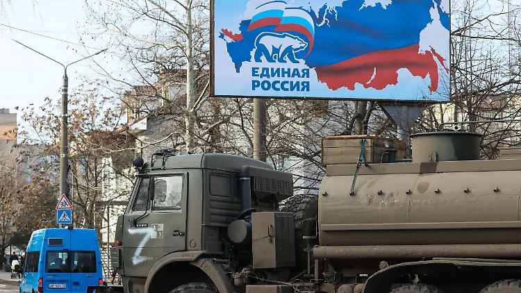 Russisches Kriegsgerät rollt vor einem Propaganda-Plakat durch das besetzte Melitopol.