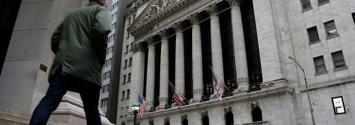 Menschen passieren die Fassade der New Yorker Börse.