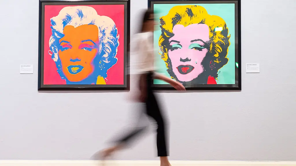 Eine-Mitarbeiterin-des-Museums-geht-in-der-Ausstellung-Andy-Warhol-im-Kunstmuseum-Pablo-Picasso-an-den-Werken-Marilyn-Monroe-Marilyn-vorbei