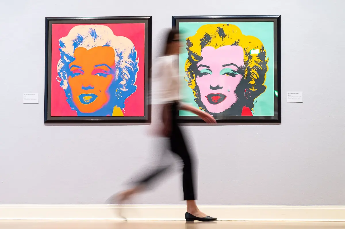 Eine-Mitarbeiterin-des-Museums-geht-in-der-Ausstellung-Andy-Warhol-im-Kunstmuseum-Pablo-Picasso-an-den-Werken-Marilyn-Monroe-Marilyn-vorbei