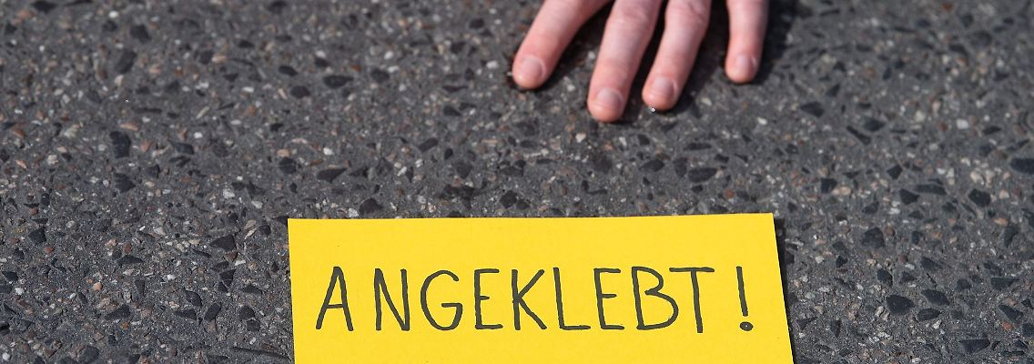Ein Demonstrant ist bei einem Protest der Gruppe "Letzte Generation" auf einer Straße festgeklebt.