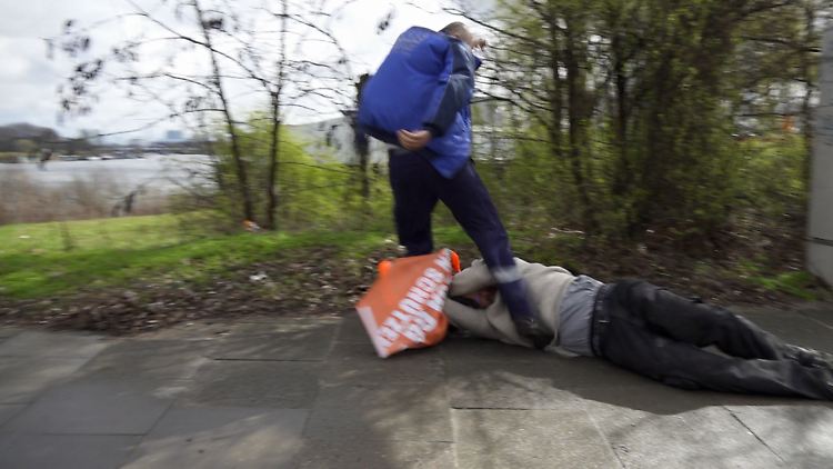 Der Fahrer zieht den Aktivisten von der Straße, verpasst ihm einen Tritt und geht anschließend zurück zu seinem LKW.