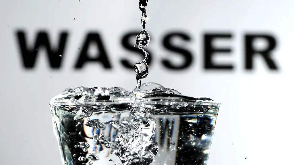 Trinkwasser-wird-vor-einem-Wasser-Schriftzug-in-ein-Wasserglas-gegossen
