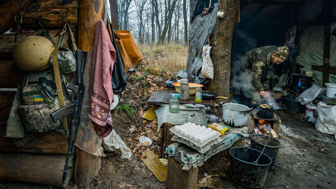 Ein ukrainischer Soldat bereitet Essen in einer improvisierten "Feldküche" zu.