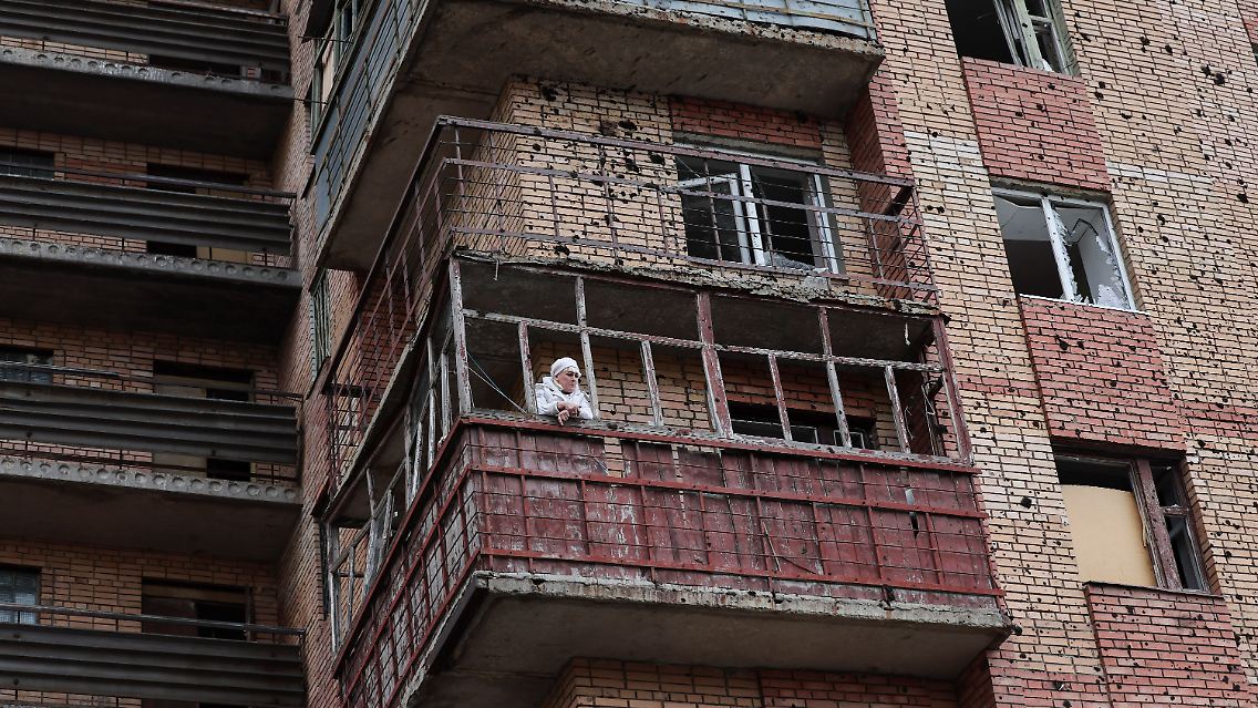 Eine Frau auf dem Balkon eines Wohnhauses nach dem Beschuss.