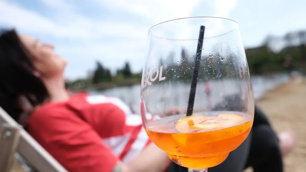 Eine-Frau-entspannt-am-Ufer-des-Heidebades-mit-einem-Aperol