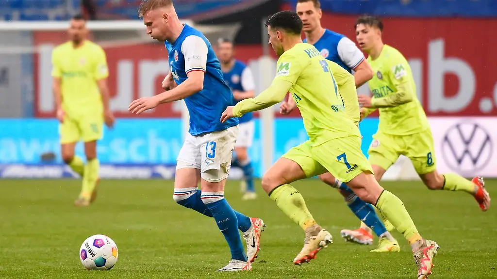 Rostocks-Kevin-Schumacher-l-behauptet-den-Ball-gegen-Wiesbadens-Robin-Heusser