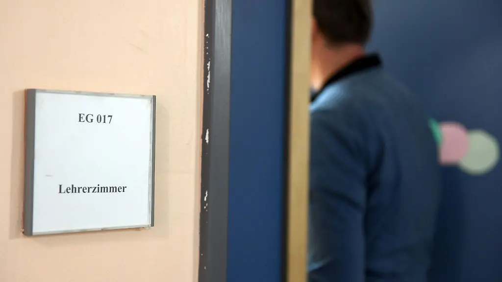 Ein-Mann-geht-an-einem-Schild-vorbei-das-den-Weg-zum-Lehrerzimmer-weist