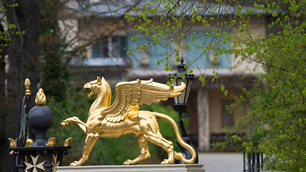 Die-vergoldete-Figur-auf-den-Saeulen-neben-dem-Greifentor-am-Kleinen-Pfoertnerhaus-des-zum-Bestand-der-Stiftung-Preussische-Schloesser-und-Gaerten-Berlin-Brandenburg-SPSG-gehoerenden-Schloss-Glienicke