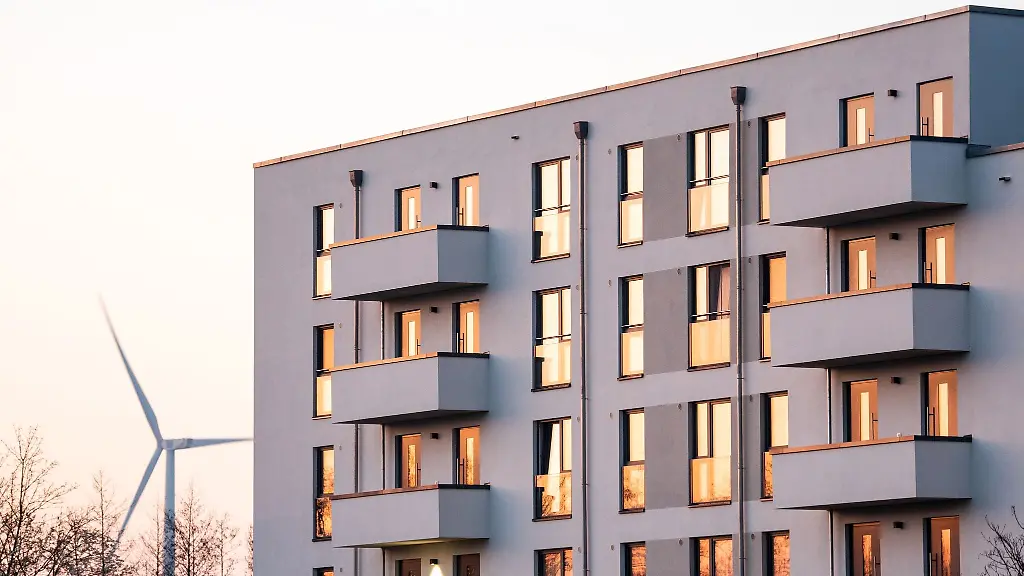 Die-aufgehende-Sonne-spiegelt-sich-am-Morgen-in-den-Fenstern-von-einem-Wohnhaus