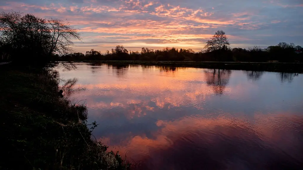 Die-aufgehende-Sonne-faerbt-den-Morgenhimmel-ueber-der-Hunte-orangerot