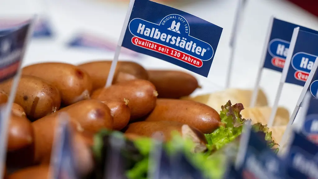 Ein-Papierfaehnchen-mit-dem-Logo-der-Marke-Halberstaedter-steckt-in-einem-Wuerstchen-am-Stand-des-Herstellers-auf-der-Gruenen-Woche