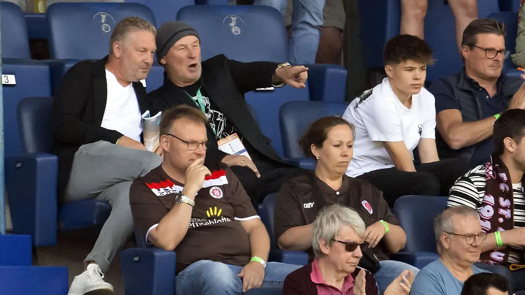 Der-Bauunternehmer-Hermann-Tecklenburg-sitzt-auf-einer-Tribuene-und-zeigt-aufs-Spielfeld