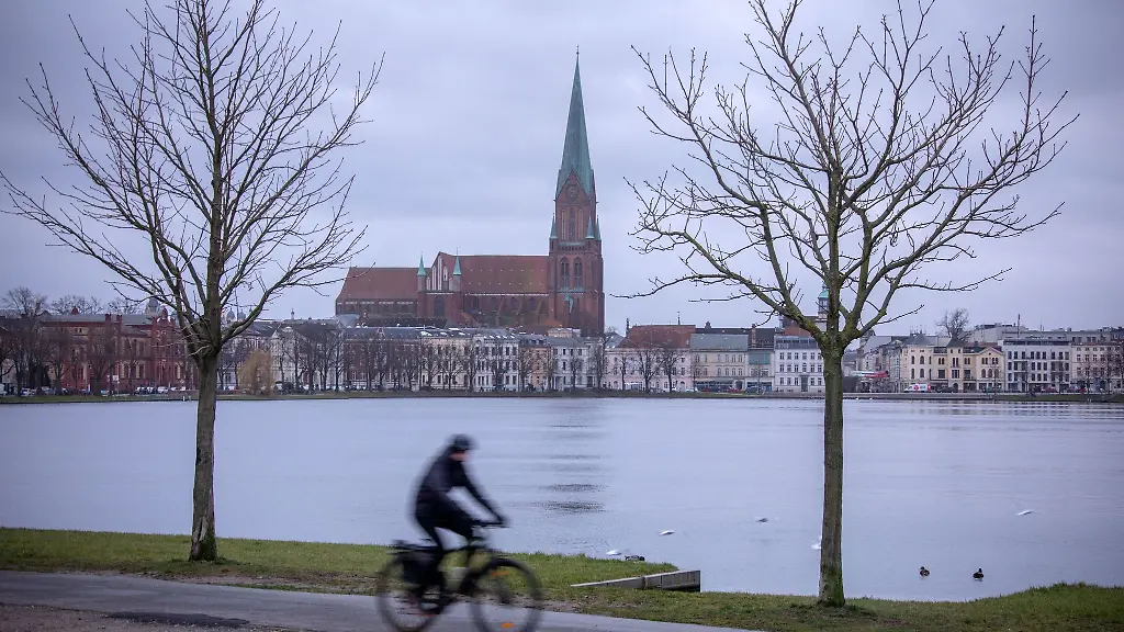 Ein-Radfahrer-faehrt-im-Stadtzentrum-von-Schwerin-am-Pfaffenteich-entlang