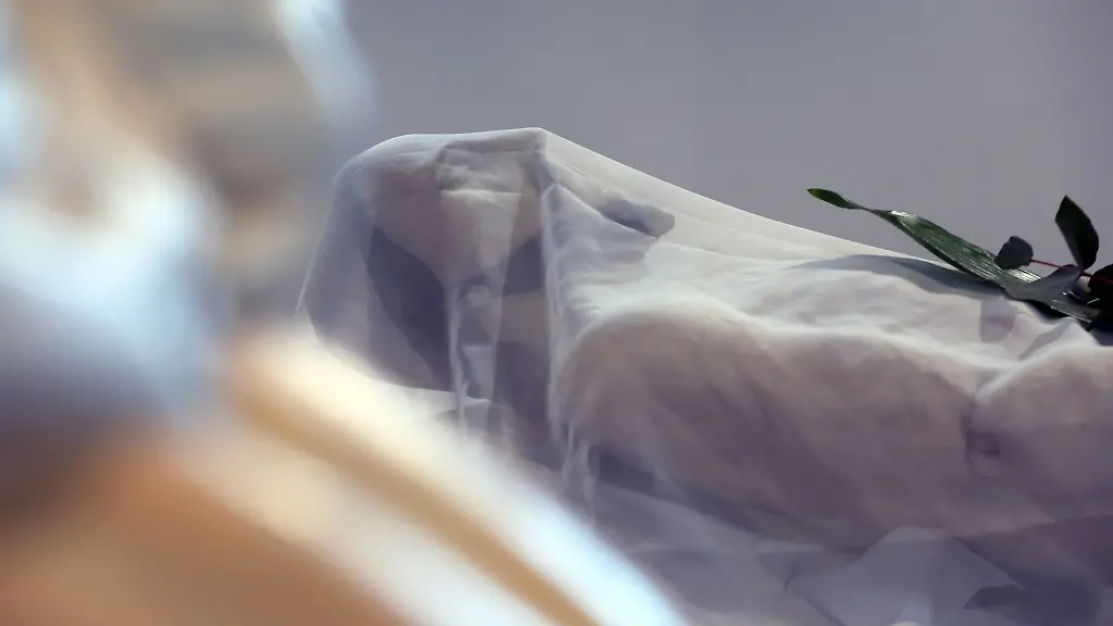 Eine-Figur-die-den-aufgebahrten-Jesus-darstellt-liegt-nach-der-Karfreitagsprozession-waehrend-eines-Gottesdienstes-im-Pfarrhof-im-Regen