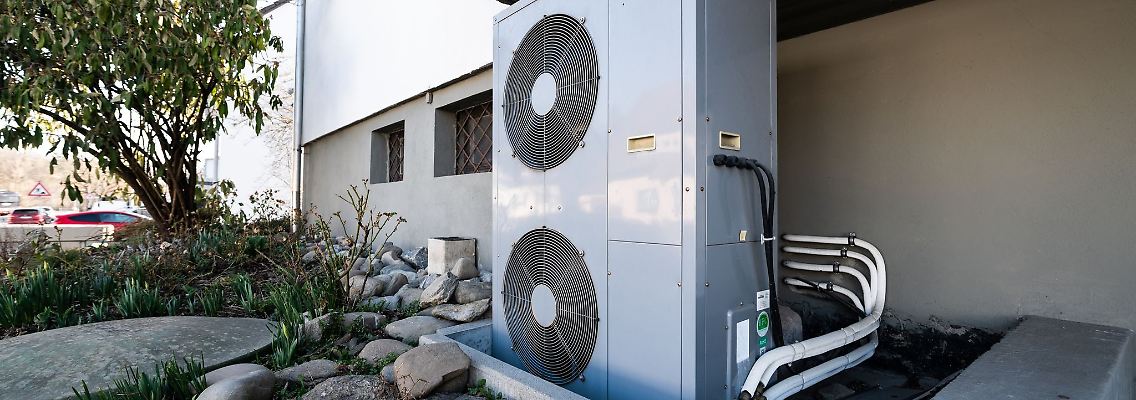 Die Lüftungsanlage einer Wärmepumpe steht vor einem Wohnhaus.