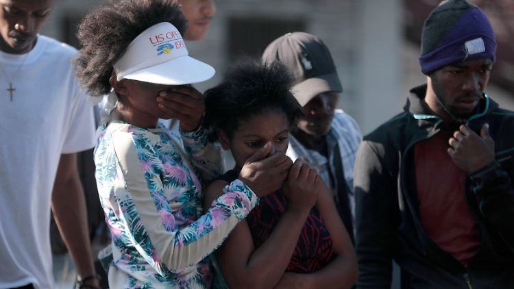 Entsetzte Anwohner beim Anblick der Leichen mutmaßlicher Bandenmitglieder, die in Port-au-Prince von einem Mob in Brand gesteckt worden waren.
