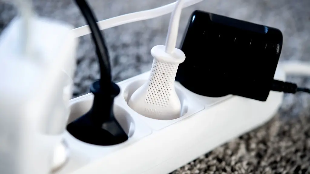 Die-Netzstecker-verschiedener-Geraete-sind-in-einem-Wohnzimmer-in-eine-Steckdosenleiste-gesteckt