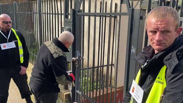 Dieser Screenshot aus einem Video zeigt, wie Vertreter des Rathauses in Begleitung der Polizei das Tor einer Schule in der Nähe der russischen Botschaft in Warschau aufbrechen.