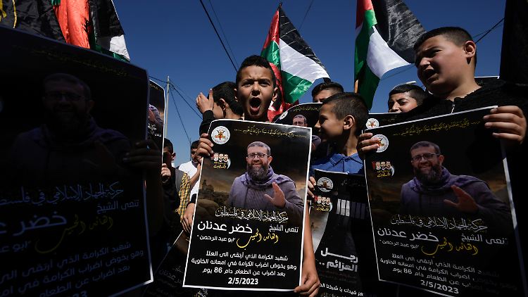 Palästinensische Kinder halten Plakate mit dem Bild von Chader Adnan im Westjordanland.