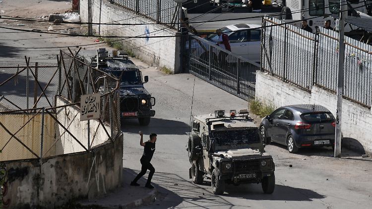 Ein Palästinenser wirft einen Stein auf einen Konvoi israelischer Militärfahrzeuge. 