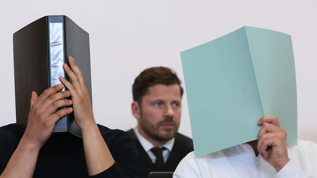 Der-Hauptangeklagte-r-sitzt-in-einem-Gerichtssaal-neben-weiteren-Angeklagten-vor-Rechtsanwalt-Harald-Stehr-M-auf-der-Anklagebank