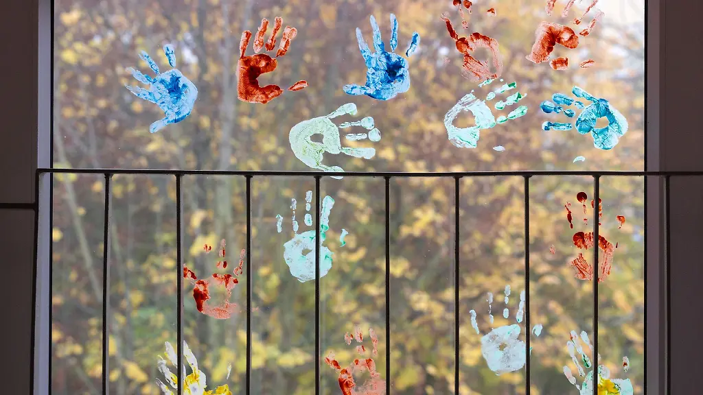 Kinder-haben-in-einem-Kindergarten-farbige-Abdruecke-ihrer-Haende-auf-einem-Fenster-hinterlassen