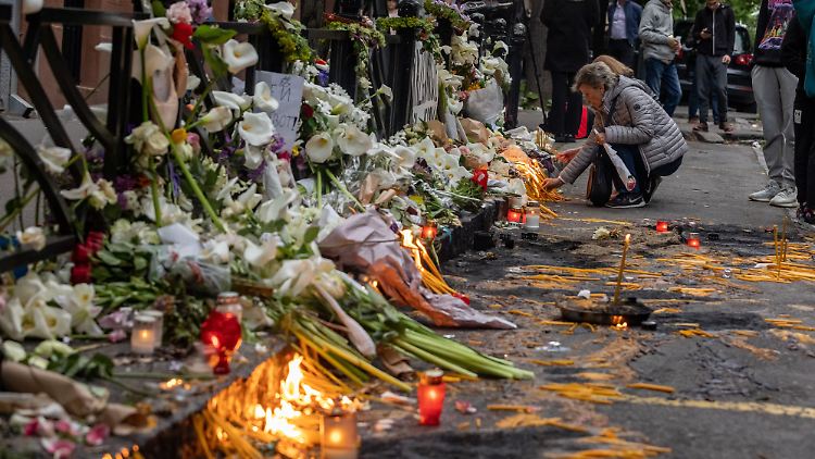 Menschen legen Blumen nieder für die getöteten Schüler und den Wachmann in Belgrad.