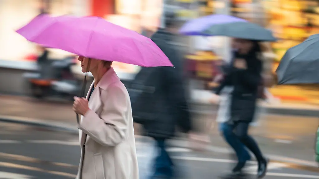 Eine-Frau-geht-bei-Regen-ueber-die-Strasse