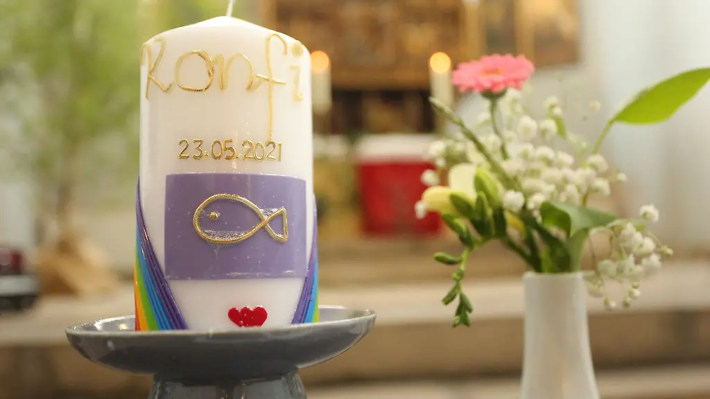 Blumenschmuck-und-eine-Konfirmationskerze-stehen-in-einer-Kirche