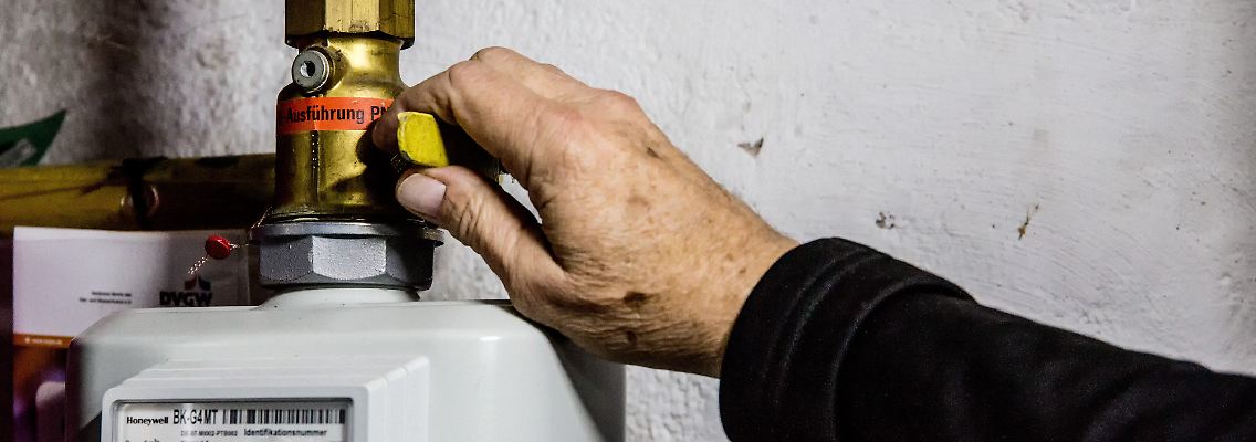 Eine Person dreht im Wohnhaus den Haupthahn der Erdgaszuleitung für die Gasheizung des Hauses ab.