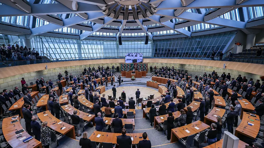 Landtagsabgeordnete-und-Gaeste-stehen-waehrend-einer-Gedenkstunde-fuer-die-Opfer-des-Nationalsozialismus-im-Landtag-von-Nordrhein-Westfalen-auf