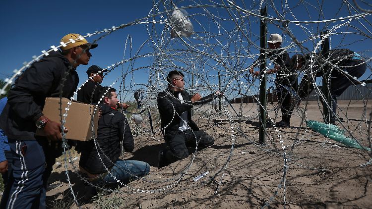Migranten versuchen einen Stacheldrahtzaun an der US-Grenze zu überwinden. 