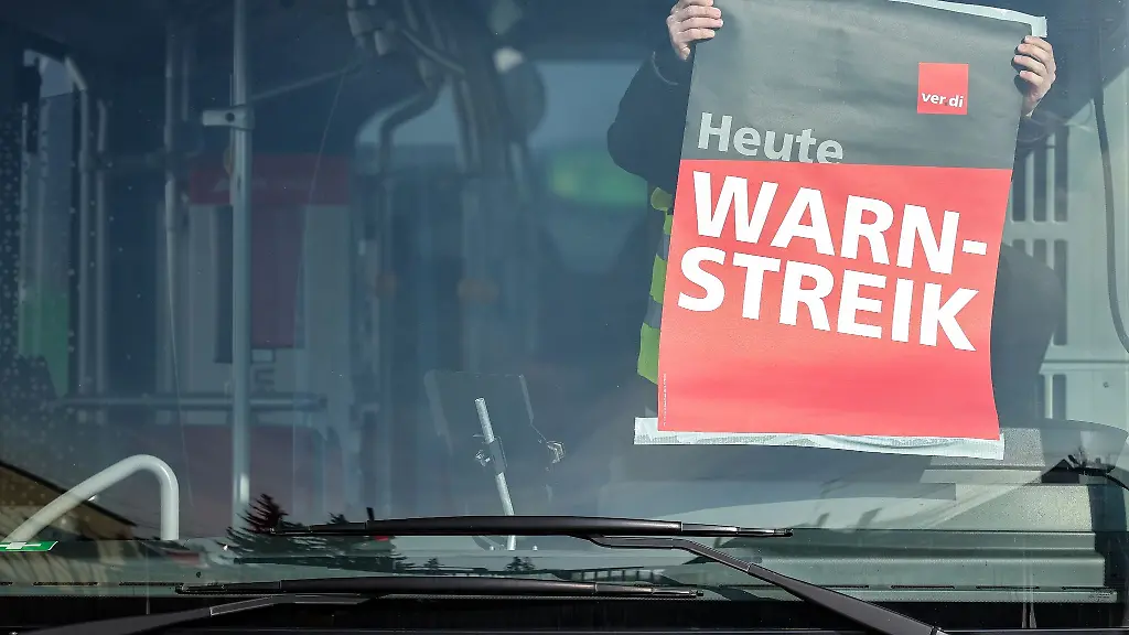 Ein-Mitarbeiter-der-Halleschen-Verkehrs-AG-HAVAG-befestigt-ein-Warnstreik-Plakat-waehrend-eines-Warnstreiks-in-einem-Bus-auf-einem-Betriebshof