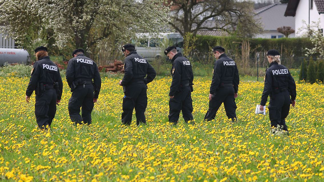 Polizisten der Bereitschaftspolizei durchstreifen eine Wiese auf der Suche nach Spuren in Altenstadt.