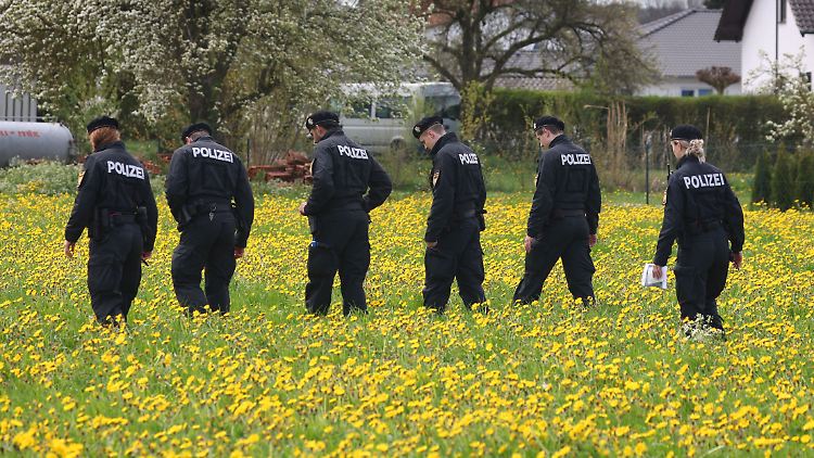 Polizisten der Bereitschaftspolizei durchstreifen eine Wiese auf der Suche nach Spuren in Altenstadt.