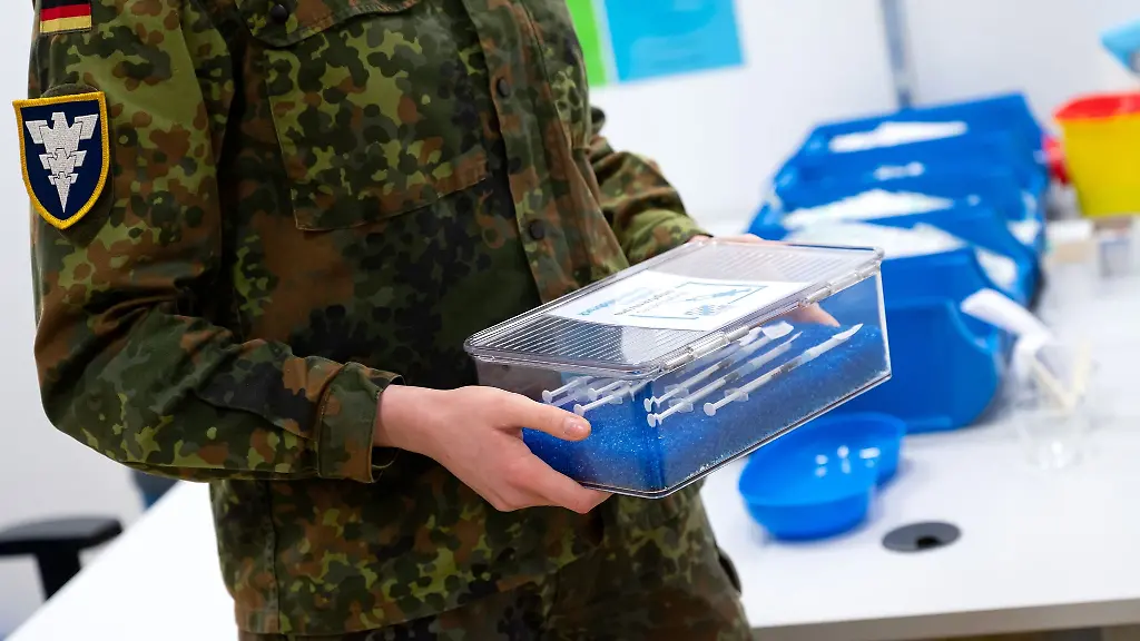 Eine-Soldatin-der-Bundeswehr-traegt-im-Impfzentrum-eine-Kiste-mit-Spritzen-gegen-das-Coronavirus-Biontech
