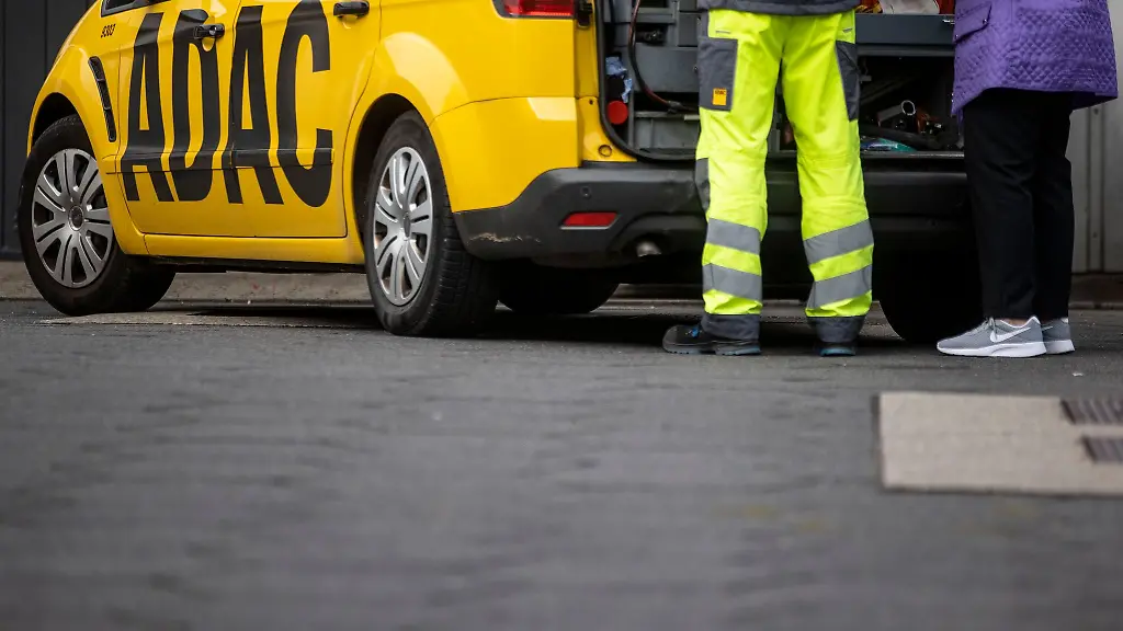 Ein-Mitarbeiter-des-ADAC-steht-mit-seinem-gelben-Fahrzeug-an-einer-Strasse-in-Duisburg-und-hilft-einer-Frau