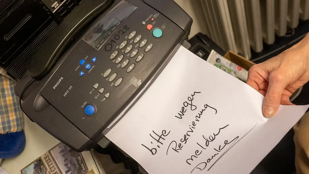 Eine-Frau-schiebt-ein-beschriftetes-Papier-in-ein-Faxgeraet