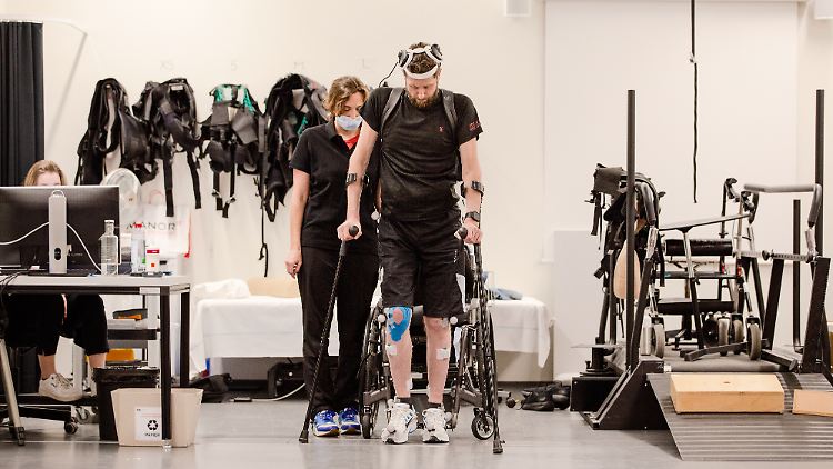 Patient und Wissenschaftler trainieren das Laufen mithilfe der "digitalen Brücke" im Universitätsspital Lausanne.