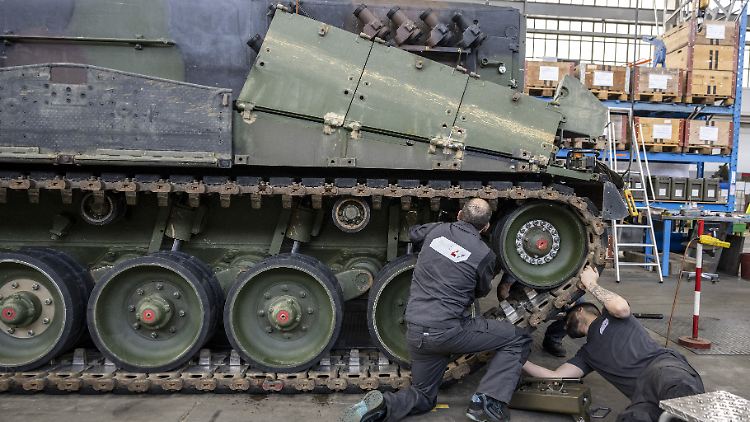 Mechaniker warten die Raupen an einem Panzer vom Typ Leopard 2 in einer Wartungshalle in Thun.