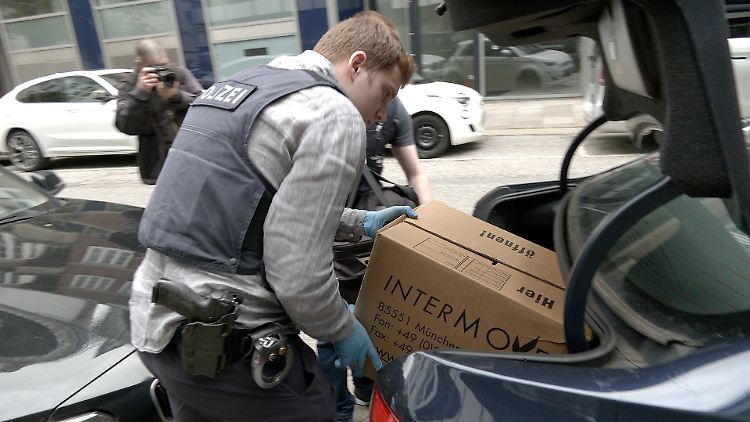 Nach einer Durchsuchung im Zuge der bundesweiten Razzia belädt ein Polizist ein ziviles Polizeifahrzeug.